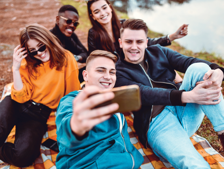 young people sitting on the ground taking a selfie